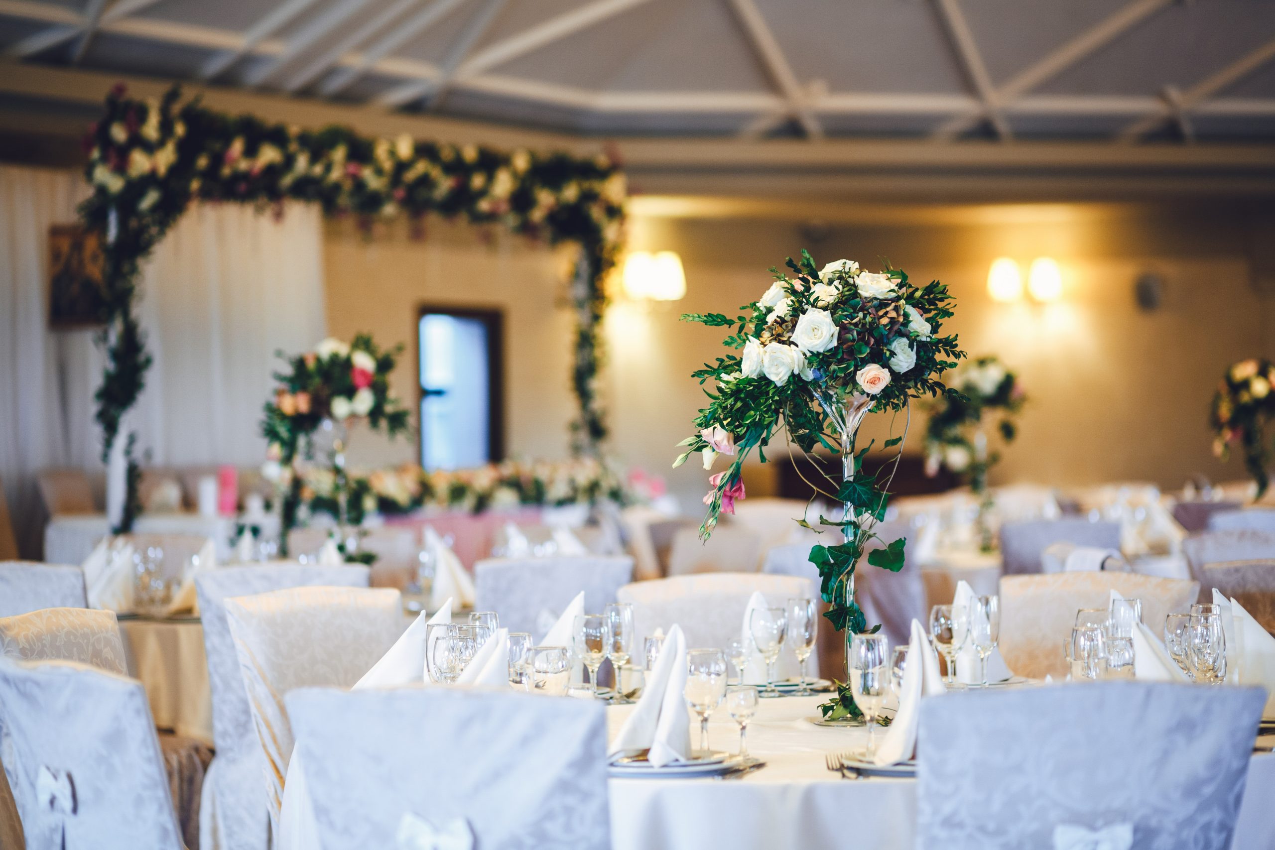 Restaurant hall with tables decorated with tall vases with roses